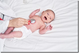 Adorable caucasian baby having heart examination with stethoscope crying at bedroom