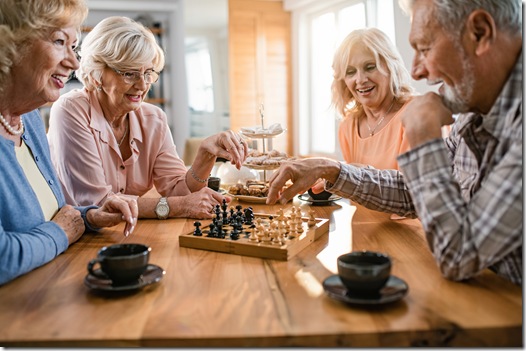 Group of happy seniors playing chess at home.