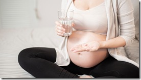 Close up pregnant woman eating vitamin pills 
